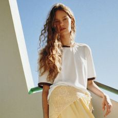 A model wearing a white baseball T-shirt with brown trim and yellow shorts from Loeffler Randall's Long Weekend Collection.