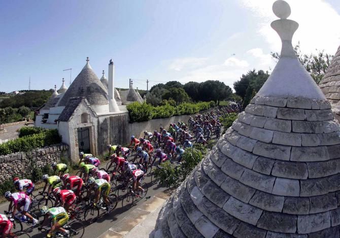 The Giro peloton passes some trulli in the Puglia region of southern Italy