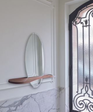 A round hallway mirror idea with American Walnut shelf by Ligne Roset