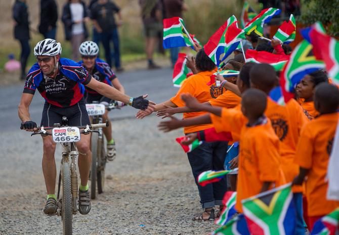 Ilaria Balzarotti and partner ride pass local school kids during the prologue