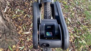 a black city bike is photographed with the CLIP e-bike conversion kit attached to the front wheel