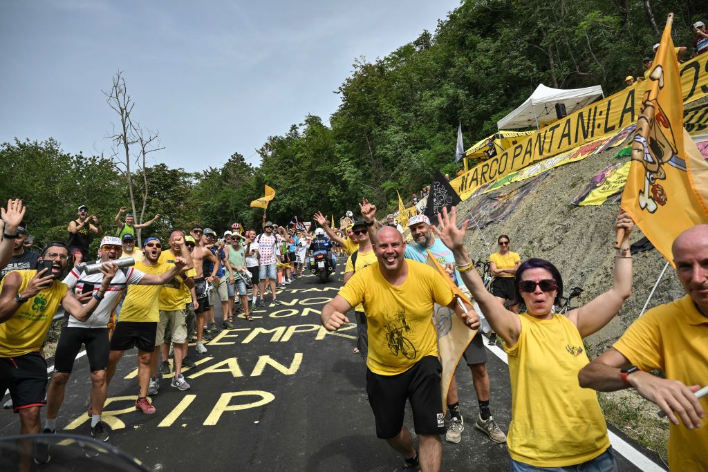 Spectators wear attire and wave flags and banners celebrating the late Italian rider Marco Pantano in the Barbotto ascent during the 1st stage of the 111th edition of the Tour de France cycling race, 206 km between Florence and Rimini, in Italy, on June 29, 2024. (Photo by Marco BERTORELLO / AFP)