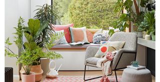 Living room with window overlooking garden with window seat and lots of houseplants to show how to bring positive energy into your home