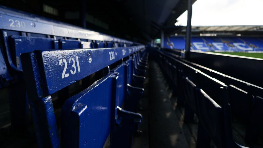 A close up of the blue painted wooden seats at Goodison Park with EFC on the chairs in the stand in the background.