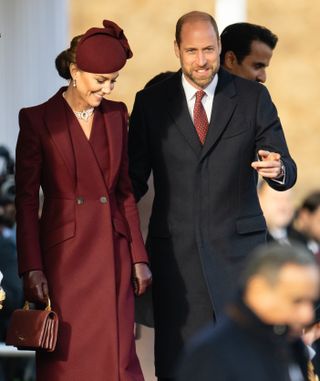 Kate Middleton wears a maroon coat and matching hat as Prince William guides her