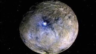 A gray rocky planet with blue lights on its surface glows in the darkness of space