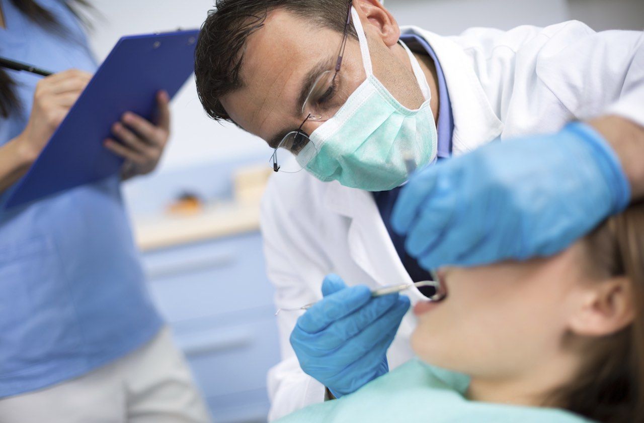 Dentist verycarefullycheck up and repair tooth of his young female patient