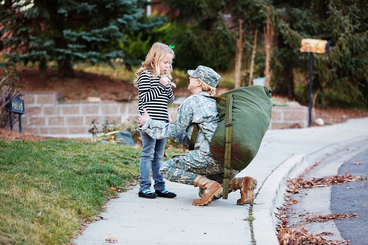 Military mother in uniform saying goodbye other daughter.