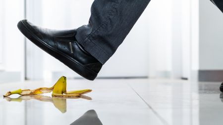 A man is about to step on a banana peel.