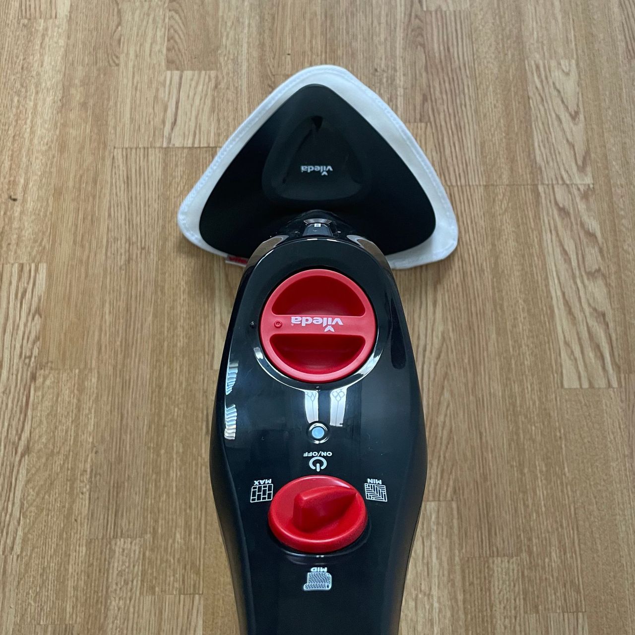 Black Vileda Steam Mop Plus with red controls on laminate flooring