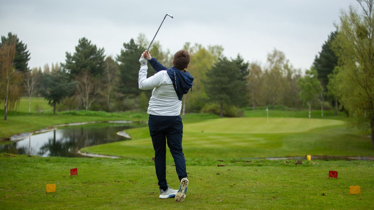 Golfer hits a shot into a downhill par 3