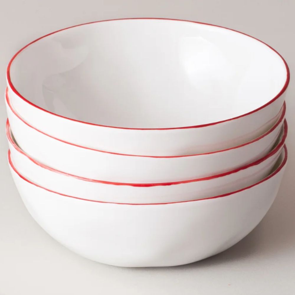 Stack of four white cereal bowls with bright red rims