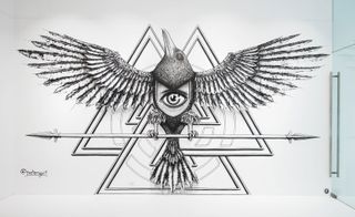 Street art displaying a large drawing with a large eye in the middle of its body and its wings open holding onto a spear.