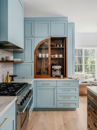 a light blue kitchen with a wooden arch coffee cabinet