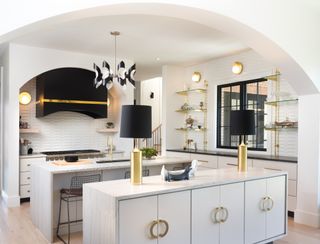 white kitchen with two kitchen islands, gold and black accents
