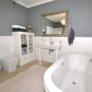 bathroom with bathtub and grey wall and white cupboard