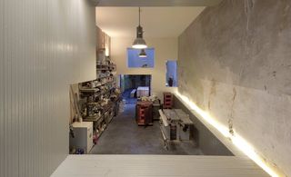 Workshop space captured from afar featuring grey walls, grey floors and white ceiling with ceiling lights.