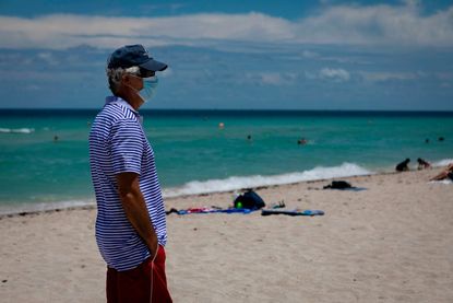 A man wears a mask on the beach in Miami.