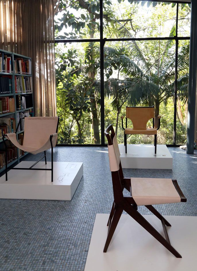 Three different chairs on plinths in a library setting