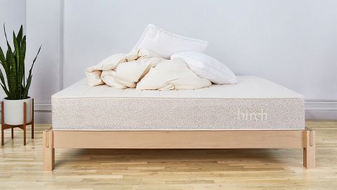 The Birch Natural Mattress on a bed with some bedding piled on top of it