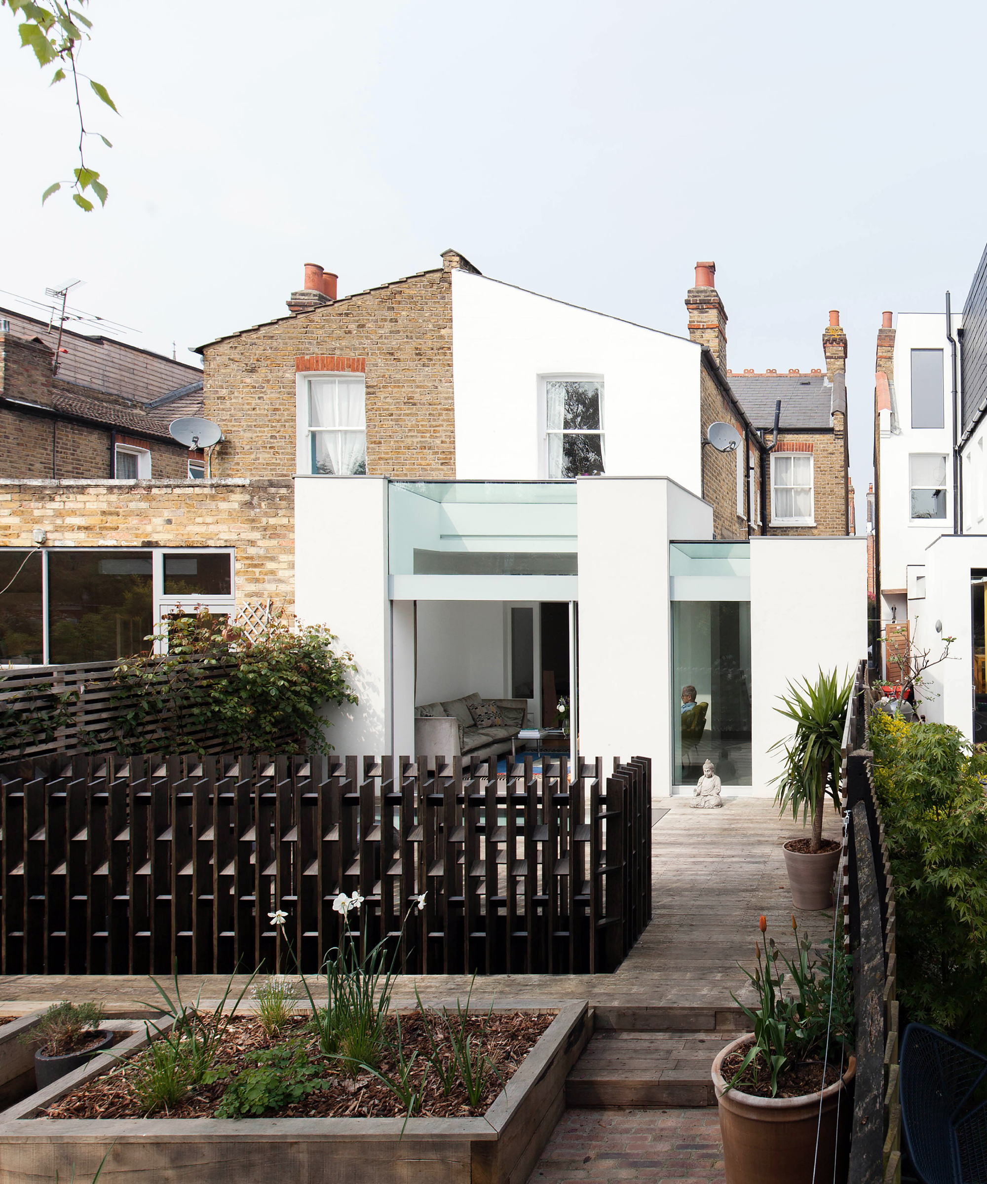 white and glass wrap around extension on semi-detached brich and white painted terraced house