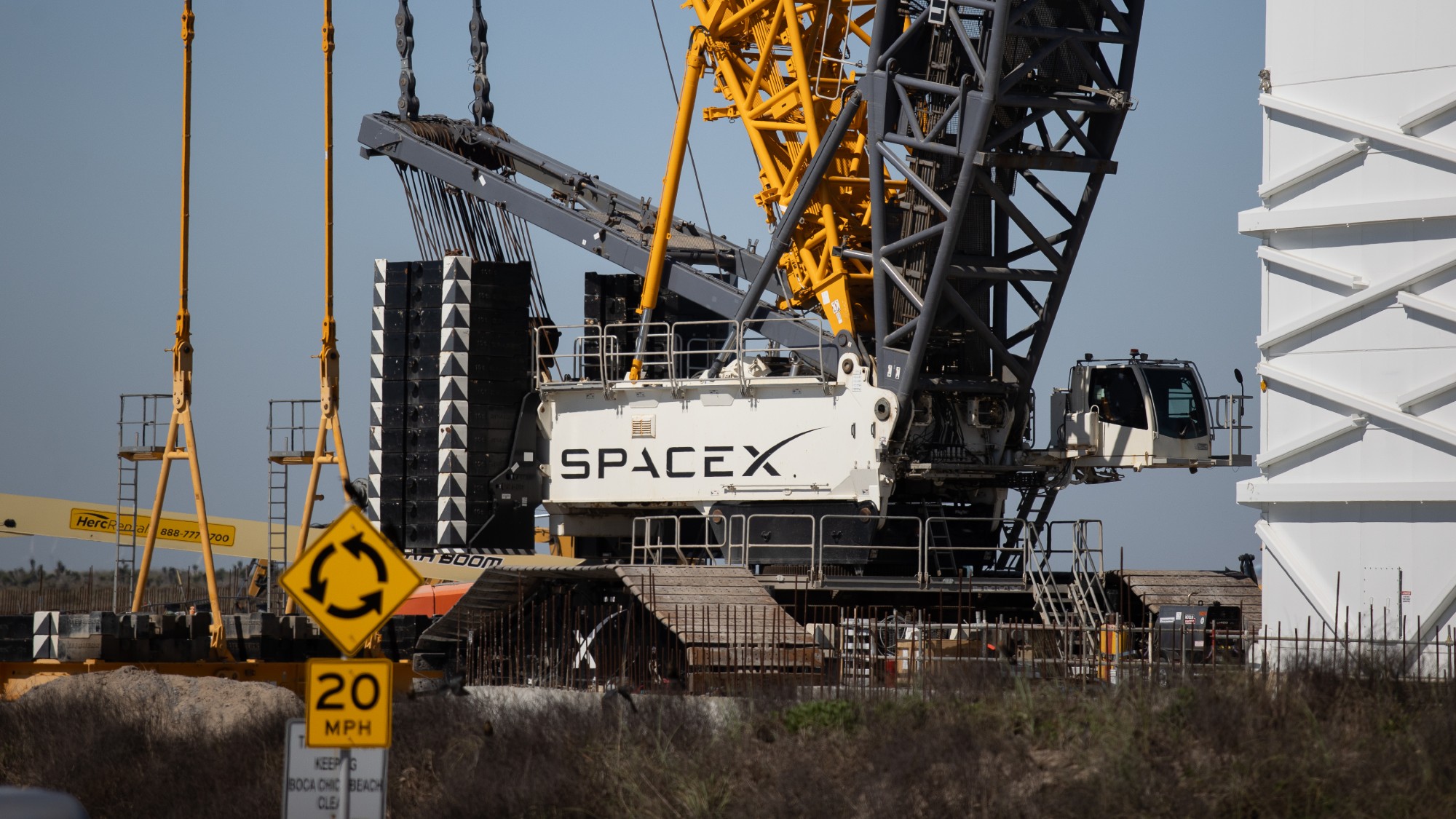 construction underway at the SpaceX site in Texas. the SpaceX logo is visible, as are a bunch of cranes. 