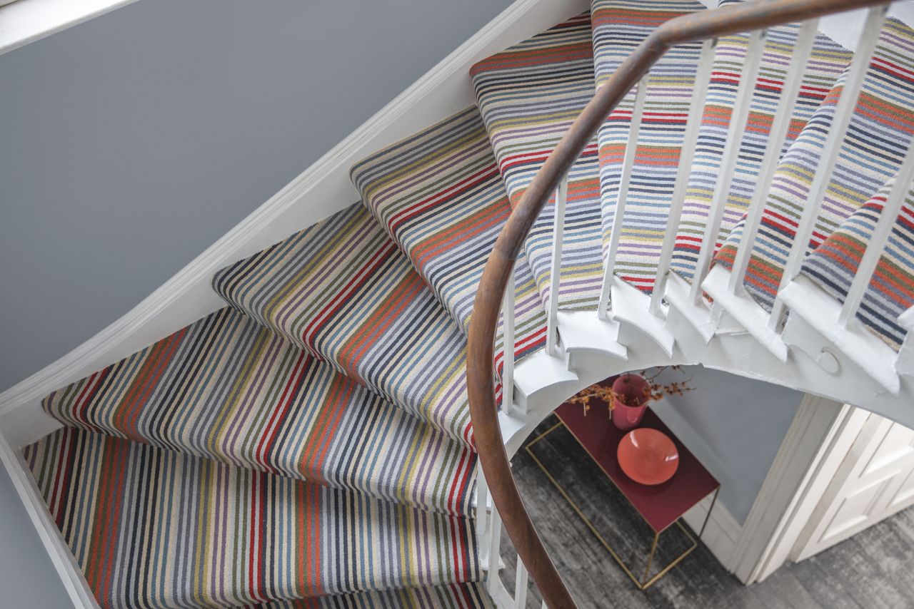 View of curved staircase carpet ideas from above with grey wall and striped carpet