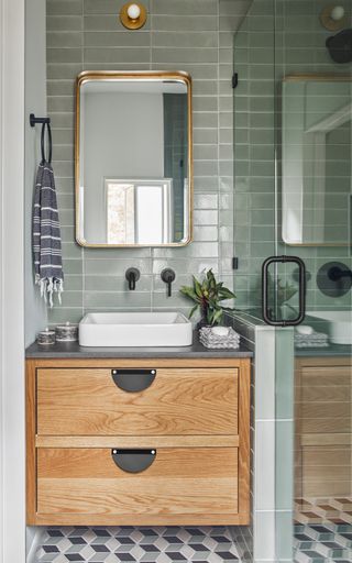 Rosemary green colored straight set tiles around white basin with wooden cabinet