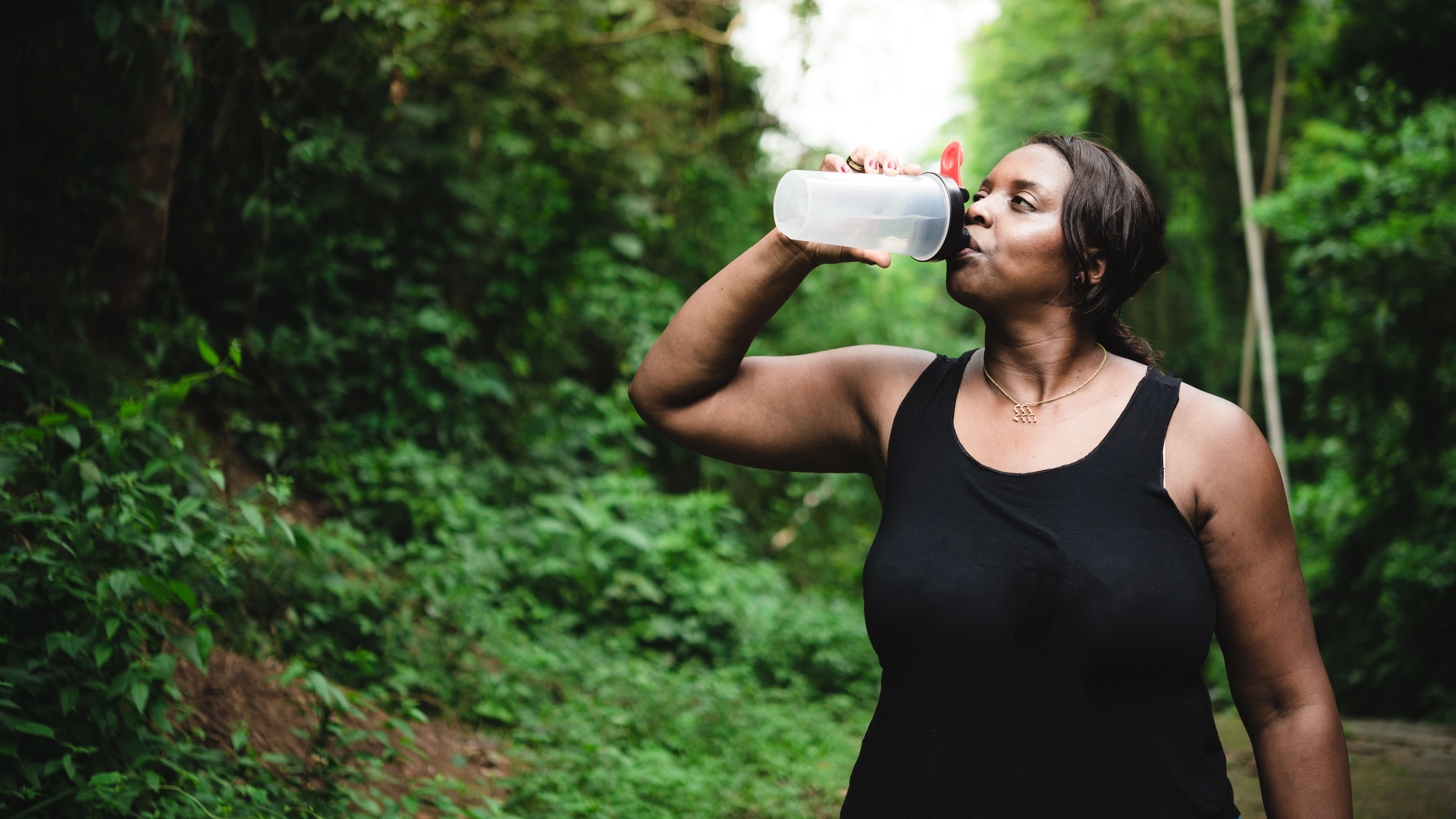 A woman drinking from a bottle while exercising