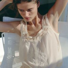 woman wears cream blouse and cream shorts