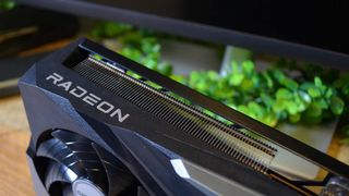 An AMD Radeon RX 6950 XT on a desk in front of a plant