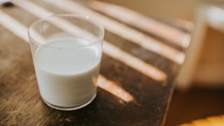 Glass of milk sitting on a table dappled in sunlight