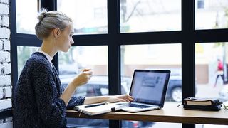 A woman remote working from a cafe using the cloud
