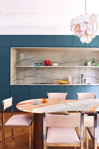 blue kitchen with marble backsplash and pink chairs