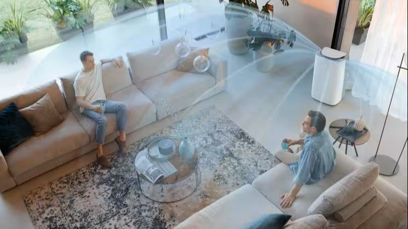 De'Longhi air conditioner in room with two people, and lines representing movement of air