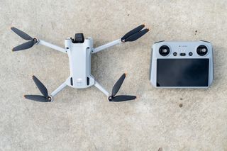 En drone av typen DJI Mini 3 Pro liggende på bakken.