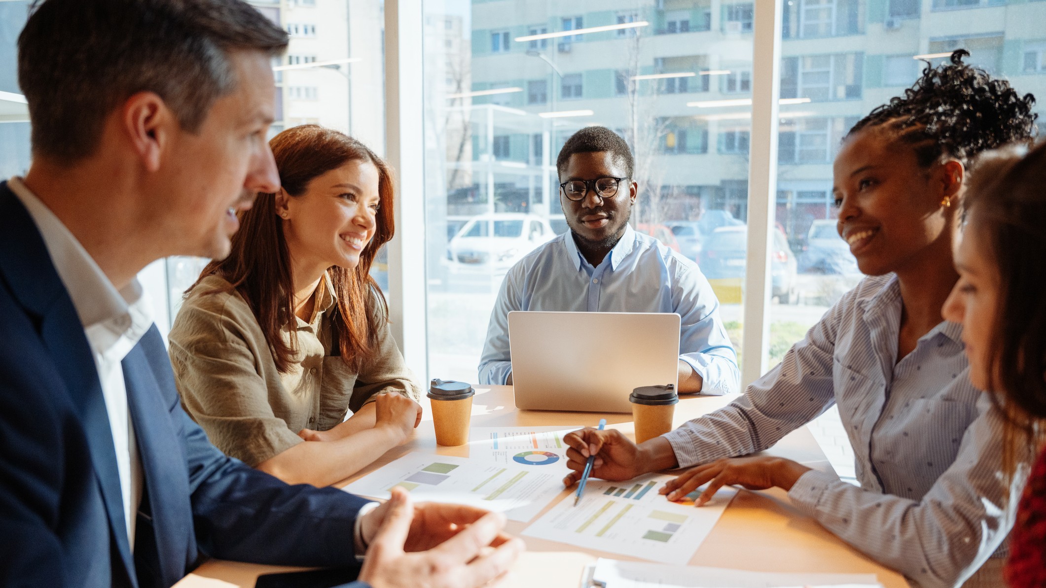 a group of diverse people seated around a table looking at financial charts 