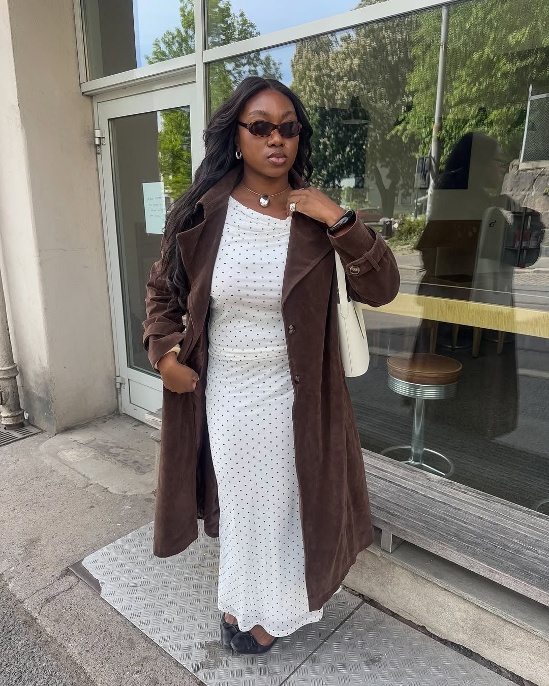 @nnennaechem wears a suede trench coat with a polkadot dress