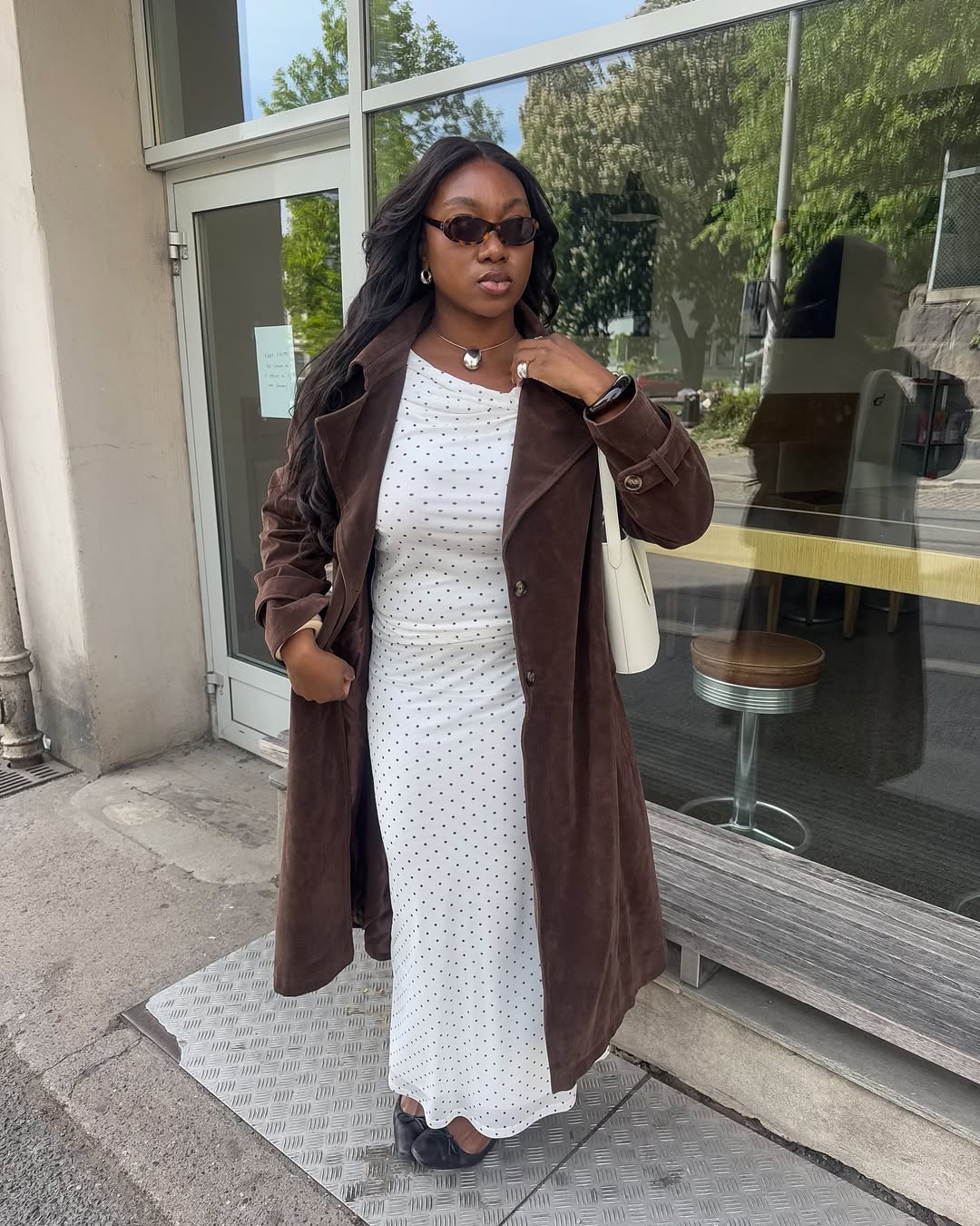 @nnennaechem wears a suede trench coat with a polkadot dress