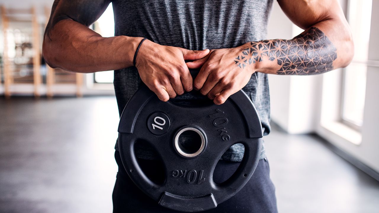 Portrait of attractive sportsman with heavy weight plate in fitness club