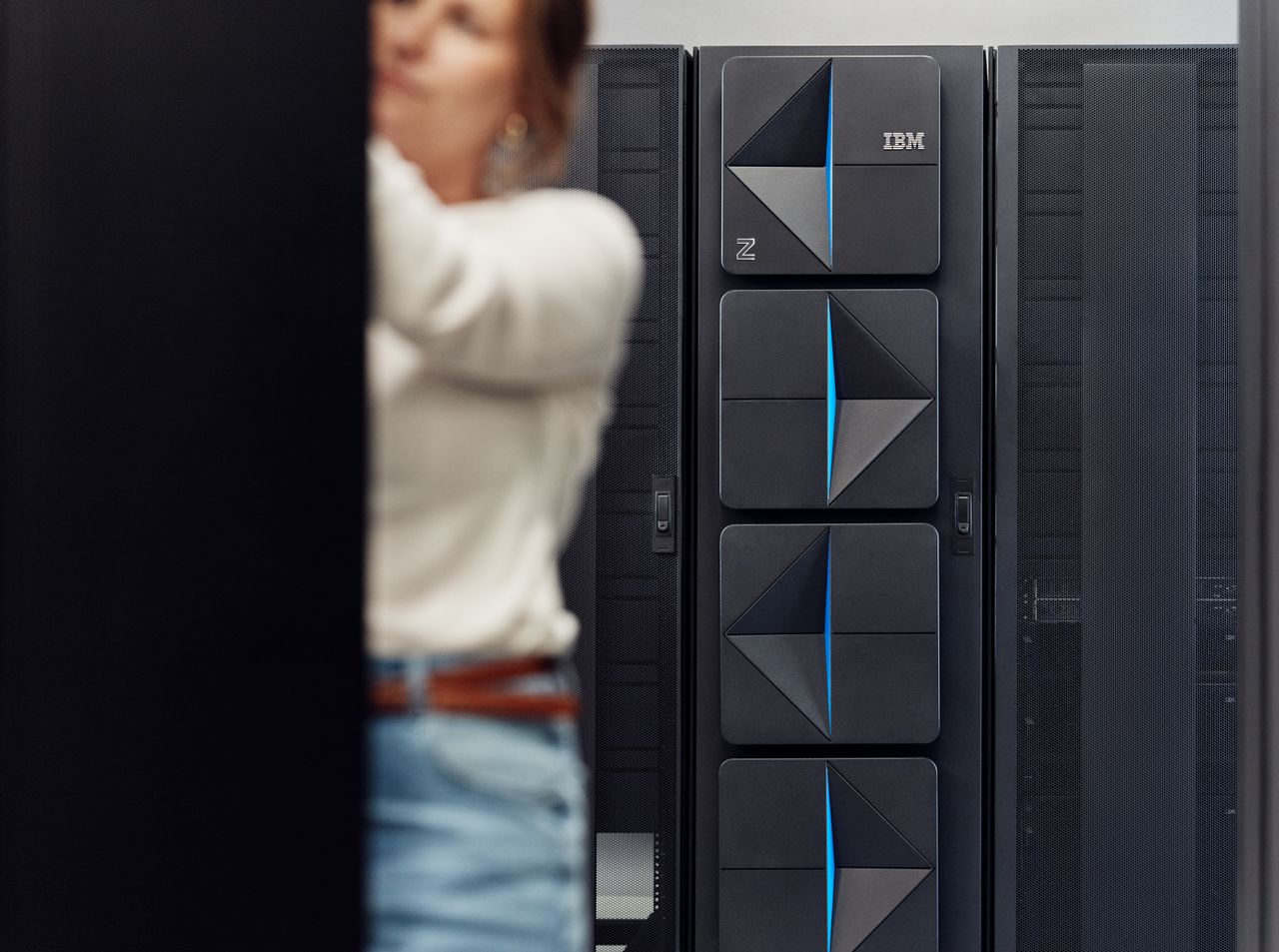 IBM z17 server racks pictured in a data center, with worker performing maintenance in foreground.