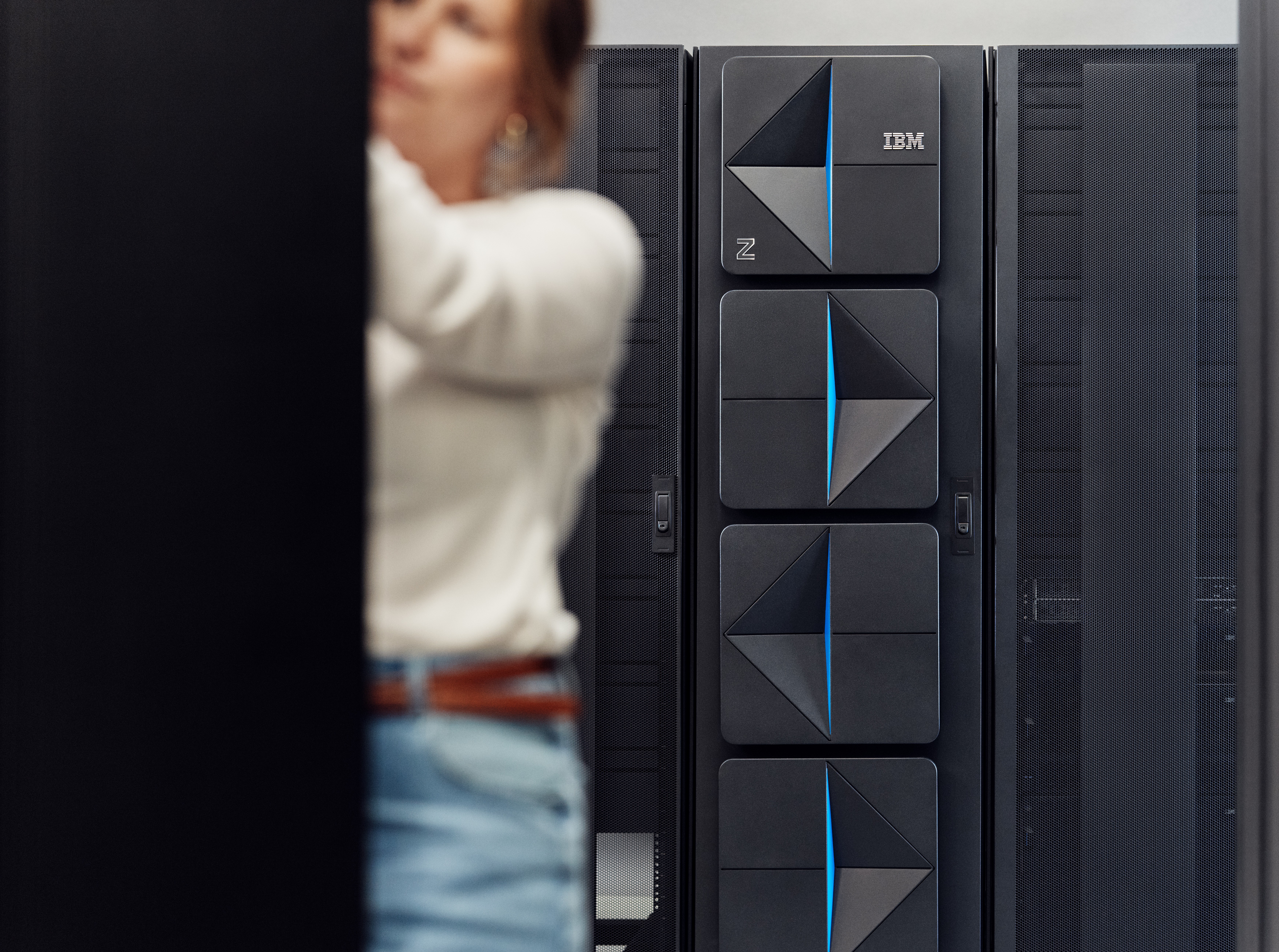 IBM z17 server racks pictured in a data center, with worker performing maintenance in foreground.