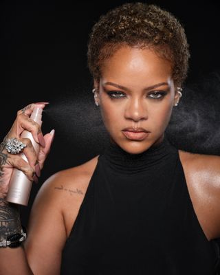 A photo of Rihanna rocking a toasted blonde pixie cut in campaign imagery for Fenty Beauty's new setting spray launch.