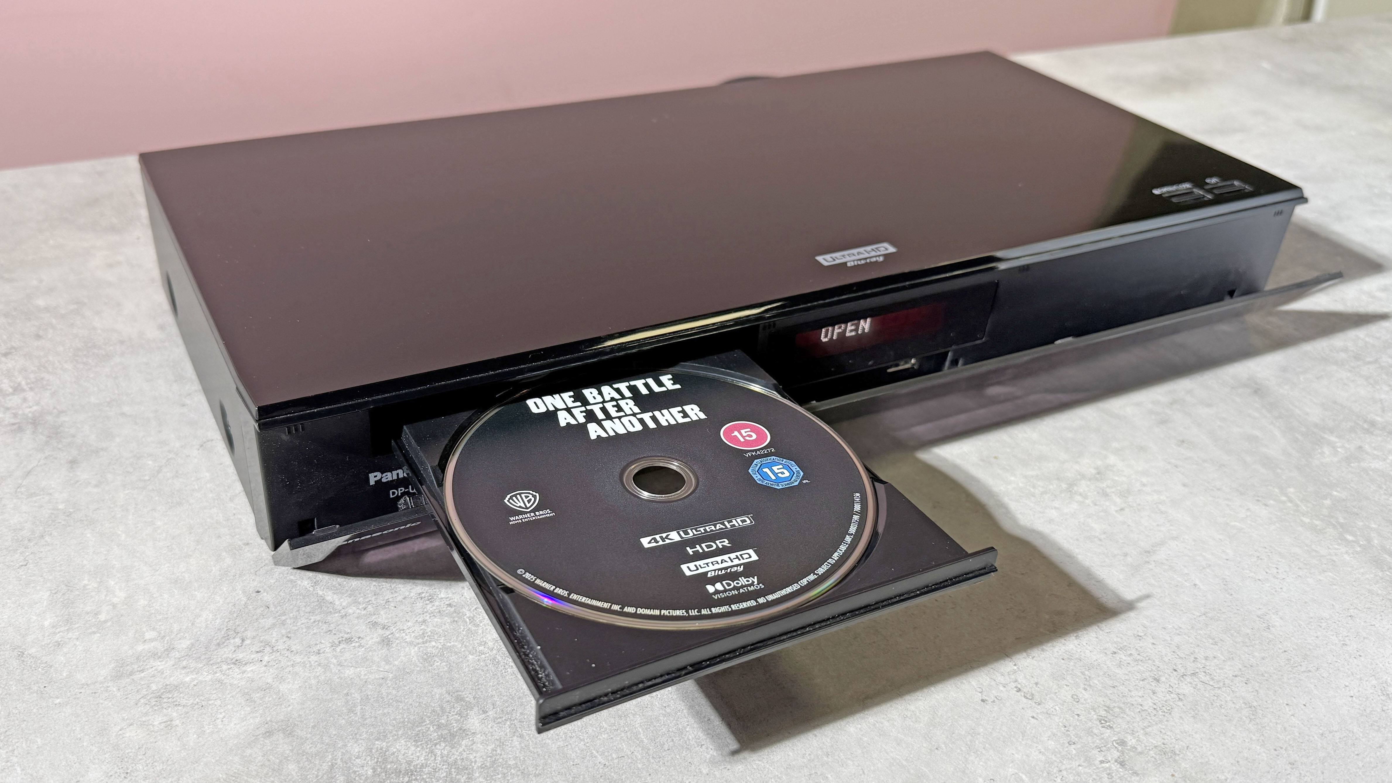 A Panasonic DP-UB820 4K Blu-ray player, with its disc tray open, and copy of One Battle After Another on 4K Blu-ray disc in the tray