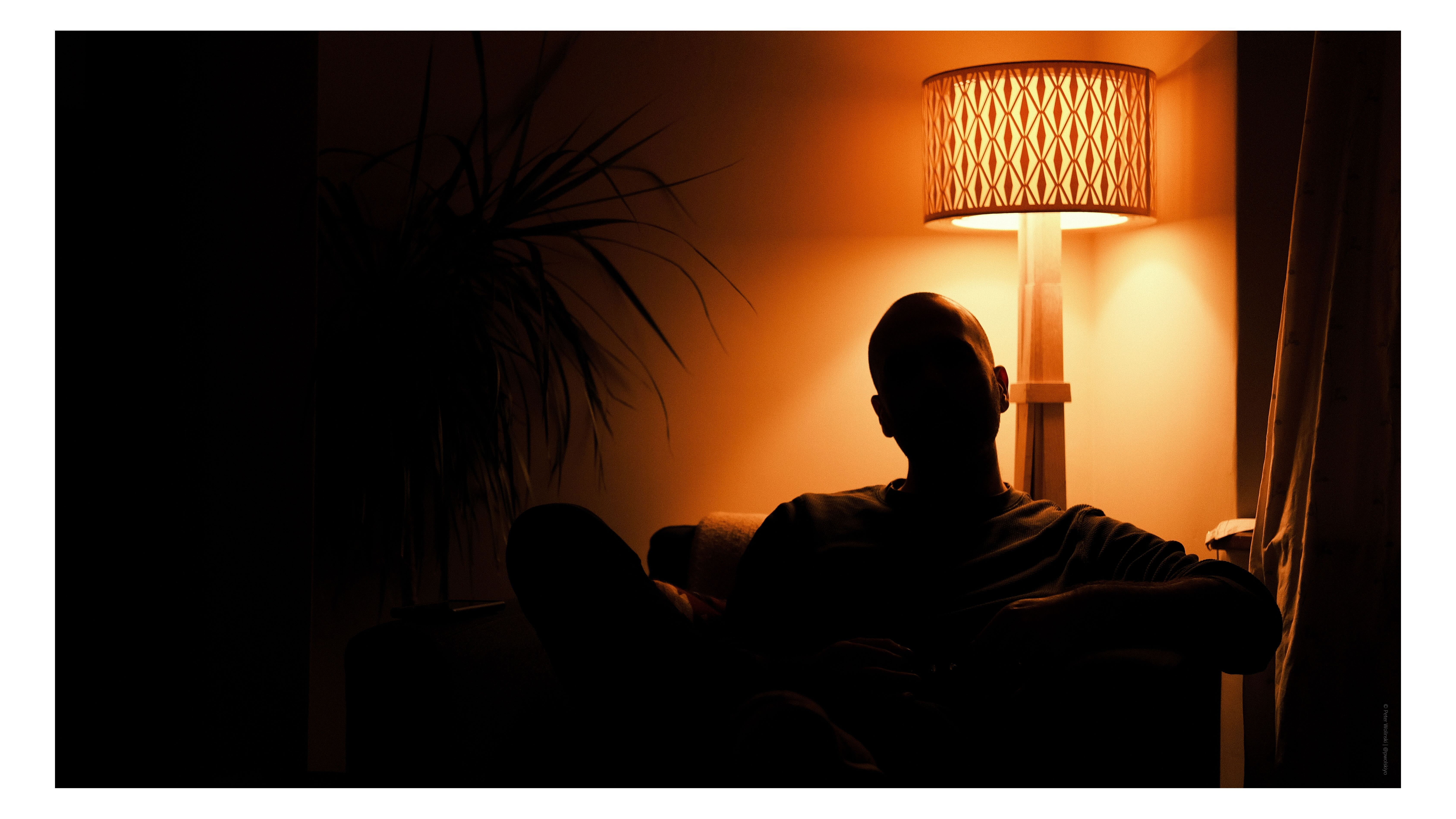 A man silhouetted against an orange light 