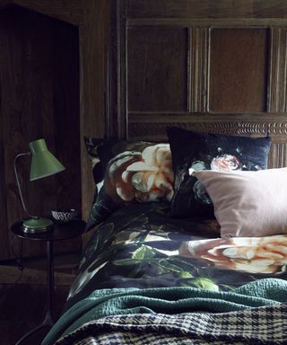 An example of dark bedrooms showing a bedroom with wood panelled walls, and dark green silk bedding