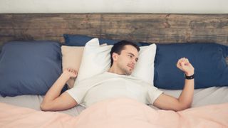 Man waking up in bed checking smartwatch