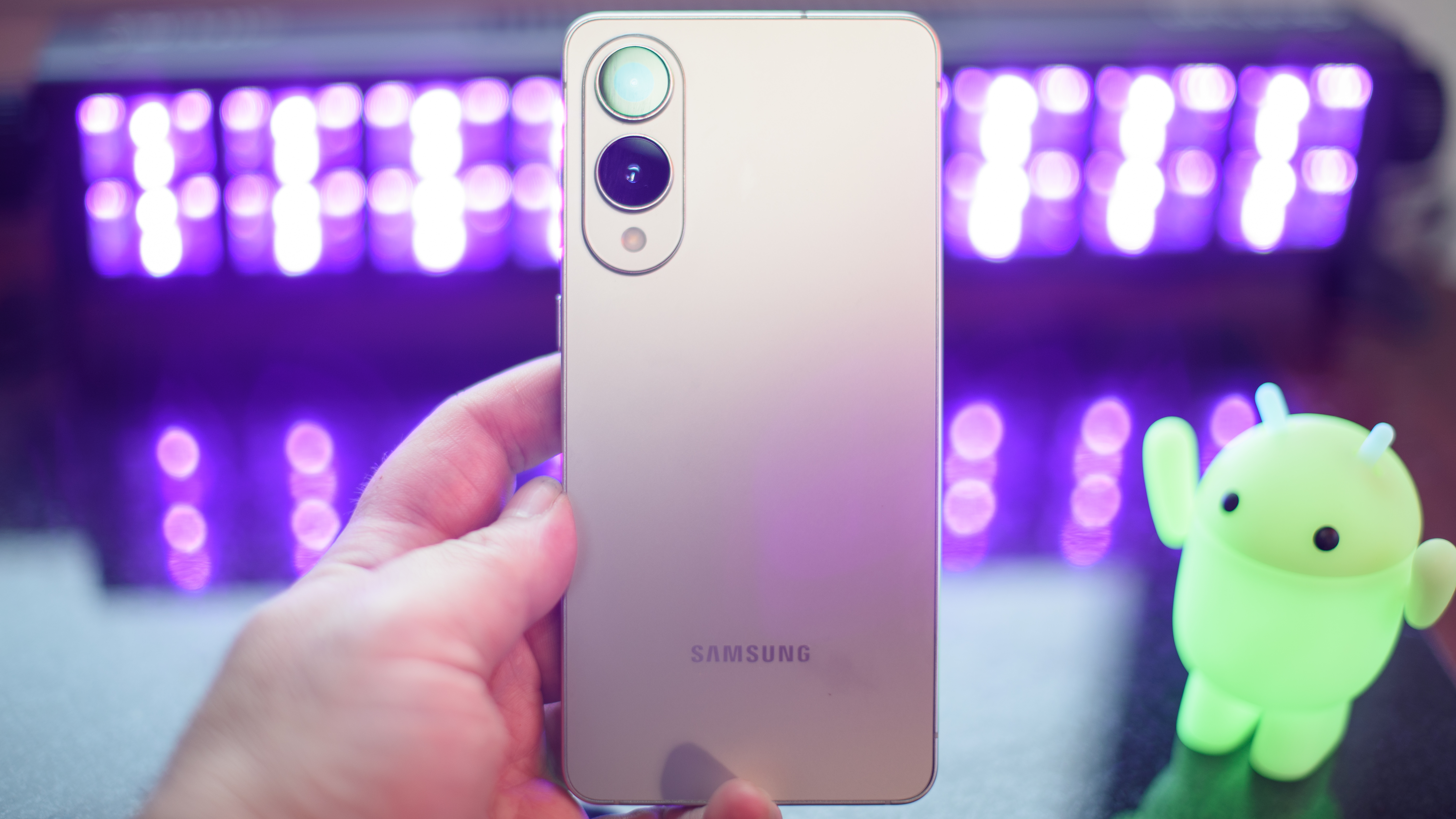 Samsung Galaxy S25 Edge showing the back panel and cameras with black lights and an Android figuring blurred in the background