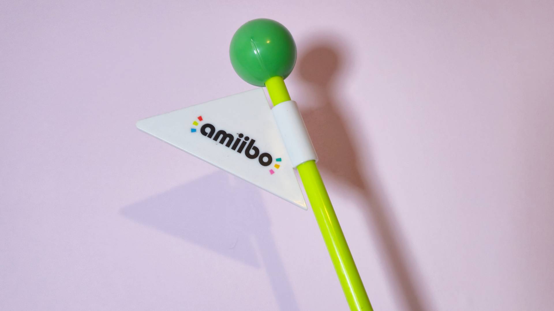 Photo of the top of the amiibo end display stand flagpole, with a pink background.