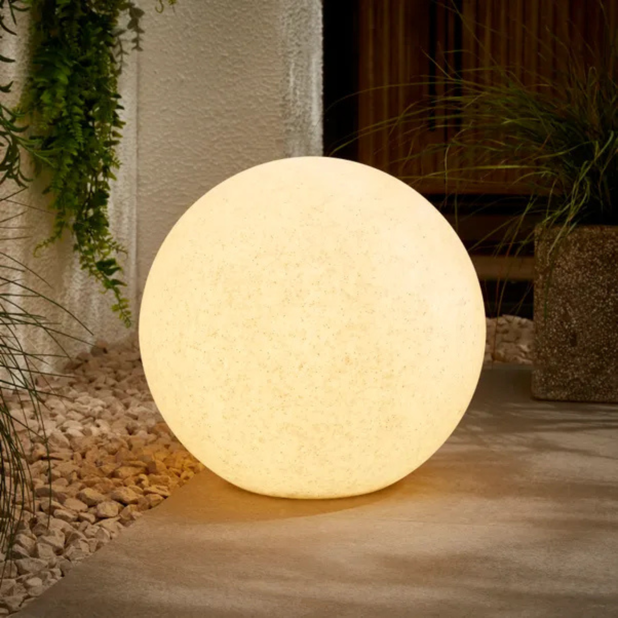 Dunelm solar mood ball light lit on a patio corner.